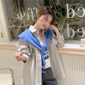 Blue knitted shawl with white stripes styled over a light grey button-down shirt