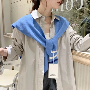 Detail of light blue striped knit shawl wrap over a beige shirt for elegant layering