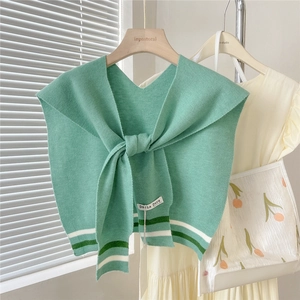 Detail of mint green knitted shawl featuring striped hem and V-neck tie closure