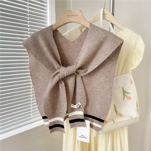 Detailed knit texture of light brown shawl featuring stylish black and white striped hem