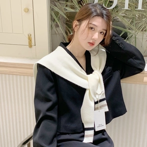 Detailed view of striped knitted shawl draped over a black blazer with brand tag