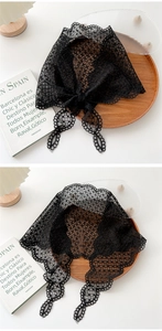 Detailed close-up of a black floral lace headscarf with scalloped edges on a wooden tray