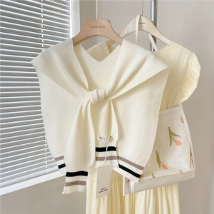 Detailed knit texture of cream white shawl with grey and black striped cuffs