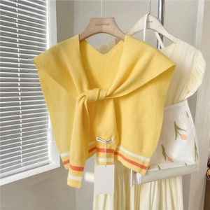 Detail of a yellow knitted shawl with colorful stripes on a wooden hanger with bag