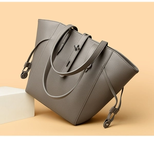 Detail of grey pebbled leather tote bag with metallic twist-lock and drawstring sides