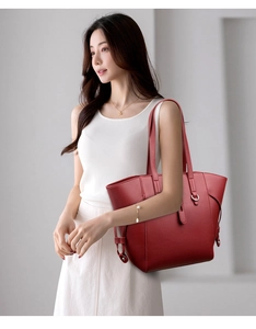 Detail of red pebbled leather tote bag showing side buckle and large capacity