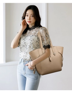Detail view of large beige tote bag with litchi grain texture and long shoulder straps