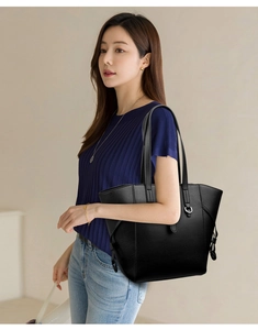 Detail of black pebbled leather tote bag showing silver ring hardware and shoulder strap