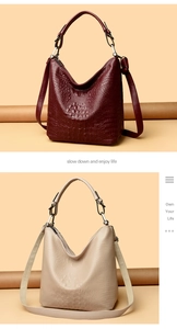 Detail of crocodile pattern embossed bucket bags in burgundy and cream with top handles