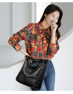 Close-up of black crocodile pattern bucket bag with adjustable wide shoulder strap on model