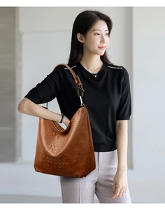 Close-up of brown crocodile pattern tote bag with wide shoulder strap and metal buckle