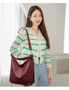 Deep red crocodile embossed hobo bag worn by a model in a bright modern interior setting