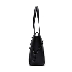 Minimalist black leather tote bag with lychee texture and side buckle detail in side view