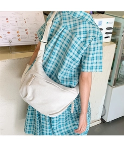 Detailed close-up of white corduroy crescent bag showing soft ribbed texture and zipper strap