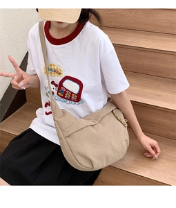 Detail of beige corduroy crescent crossbody bag with adjustable wide strap on model
