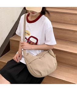 Beige corduroy crossbody dumpling bag shown on a model in a casual lifestyle setting