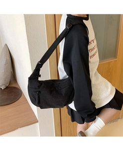 Detail view of black corduroy crossbody dumpling bag with adjustable strap and textured fabric