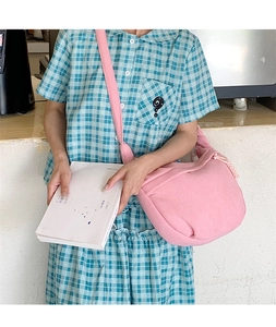 Pink corduroy crossbody bag shown on a model highlighting its casual half-moon shape