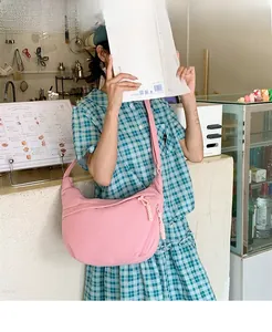 Pink corduroy crossbody dumpling bag worn in a cafe, showing spacious moon shape design