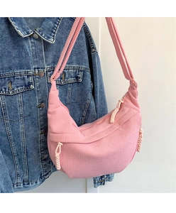 Detail of pink corduroy dumpling bag texture with braided zipper on denim jacket
