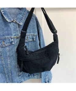 Detail of black corduroy hobo bag showing vertical ribbed texture and braided zippers