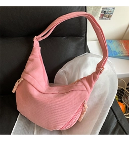 Detail of pink corduroy dumpling shoulder bag featuring vertical ribbed texture and zipper