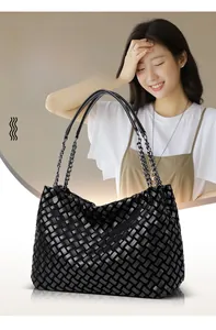 Détail du sac cabas tressé noir avec bandoulières mixtes en chaîne et en cuir souple