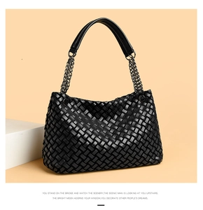 Détail d'un sac tressé noir avec bandoulière en chaîne métallique et texture quadrillée