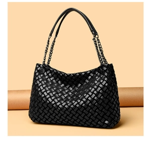 Détail d'un sac cabas en cuir tressé noir avec poignée en chaîne métallique et design tissé