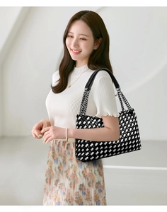 Détail du sac à bandoulière tissé à damier noir et blanc avec bandoulière en métal