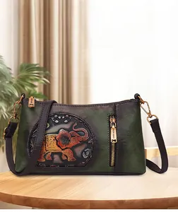 Detail of the vintage dark green crossbody bag featuring embossed orange elephant pattern