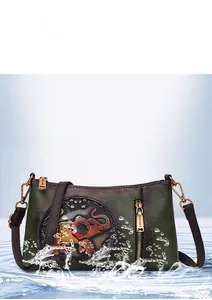 Close-up of waterproof dark green lychee grain leather crossbody bag with elephant relief