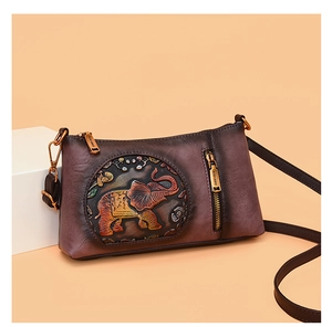 Detailed view of vintage brown leather handbag with colorful elephant relief and brass zipper