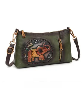 Macro view of vintage green leather crossbody bag with embossed elephant pattern detail