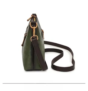 Detail view showing dark green litchi texture faux leather and side zipper pocket of the bag