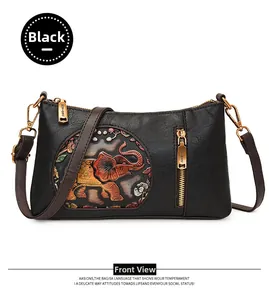 Detail of black pebbled leather crossbody bag featuring colorful embossed elephant motif