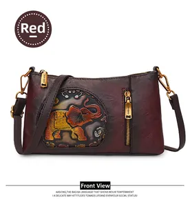 Detail of red embossed shoulder bag featuring intricate elephant and floral patterns