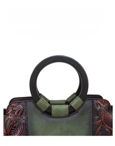 Close-up of vintage green leather handbag featuring floral embossing and wooden handles