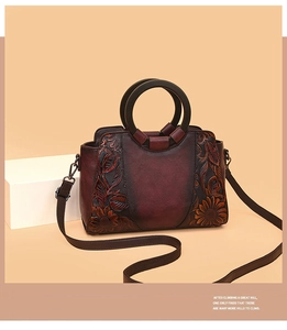 Detail of vintage burgundy leather handbag featuring exquisite sunflower embossing and round handle