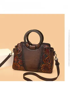 Detail of vintage brown leather handbag with sunflower embossing and round wooden handle