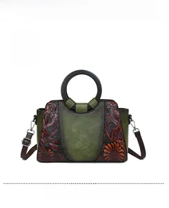 Front view of a vintage green tote bag featuring floral embossing and a wooden ring handle