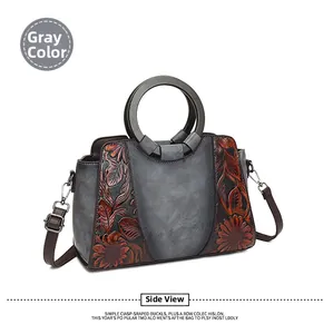 Detail of vintage gray handbag featuring embossed orange sunflower patterns and wooden handles