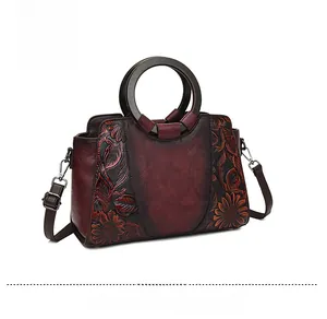 Detail of burgundy tote bag featuring vintage floral embossing and resin top handles