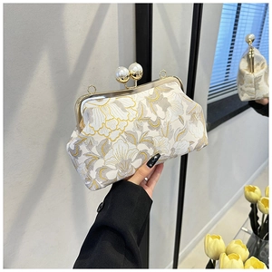 Détail de broderie florale sur pochette vintage blanche avec fermoir en perles