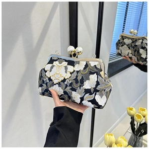 Gros plan de la broderie florale d'une pochette vintage avec fermoir à double perle