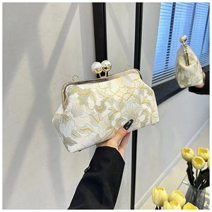 Détail d'un sac à main brodé de fleurs vintage avec fermoir perle et cadre doré élégant