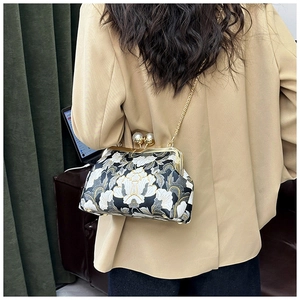 Détail du sac bandoulière brodé de fleurs vintage avec chaîne dorée et fermoir perle