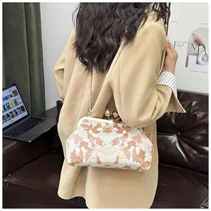 Détail d'un sac brodé vintage avec bandoulière chaîne dorée sur l'épaule du mannequin