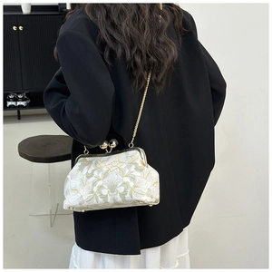 Détail de broderie florale sur un sac vintage avec bandoulière chaîne dorée