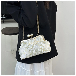 Détail d'un sac bandoulière crème avec broderie florale et fermoir perle vintage